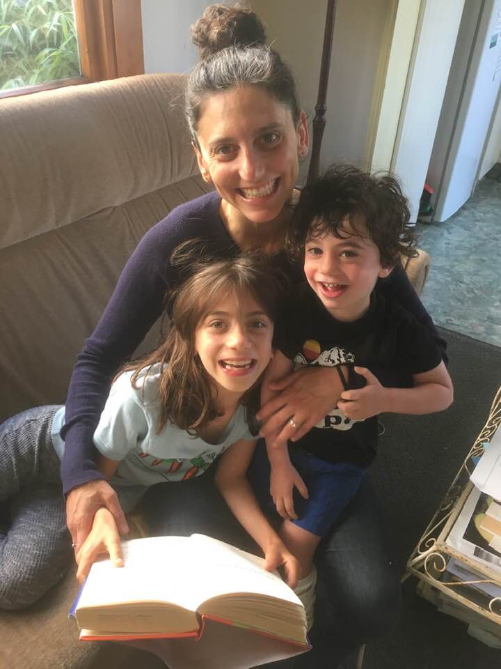 Sarah reading with her kids in her lap all smiling and looking at the camera